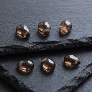 Eight smoky quartz teardrops in brown tones on dark slate