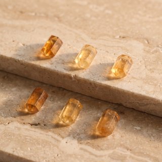 Six citrine columns scattered on travertine, each with its own shape and depth of color