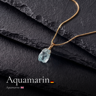 Roher Aquamarin Anhänger an Goldkette auf Schiefer mit Schriftzug Aquamarin