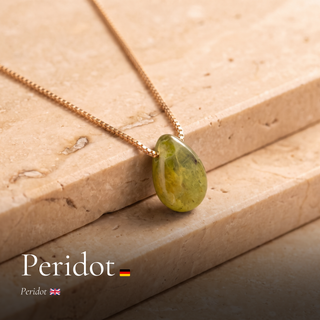 Peridot Tropfen an Goldkette auf Travertin mit Schriftzug Peridot