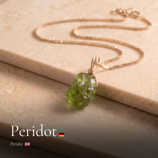 Roher Peridot Anhänger an Goldkette auf Travertin mit Schriftzug Peridot