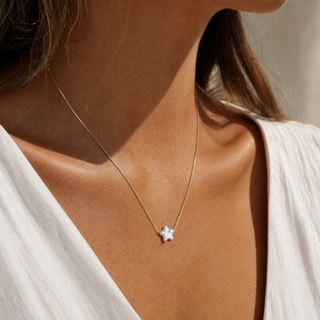 Perle Stern Kette am Hals zu weißem Oberteil, kleiner Perlenstern mittig