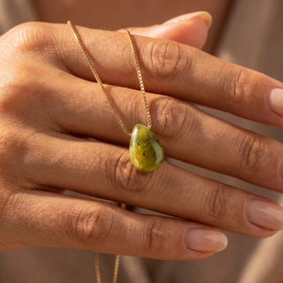 Peridot teardrop on the back of the hand, gold chain wrapped around the fingers