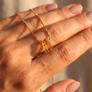 Citrine cylinder resting on the fingers, detail shot of the gold bail