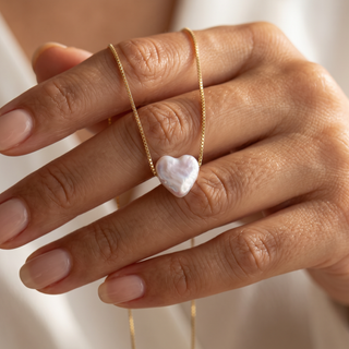 Perlenherz über die Finger gelegt, Perlglanz und feine Goldkette im Detail