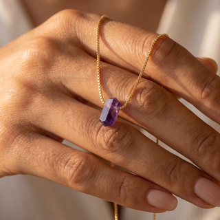 Amethyst Zylinder über die Finger gelegt, Detail der Goldöse und Kristallspitze