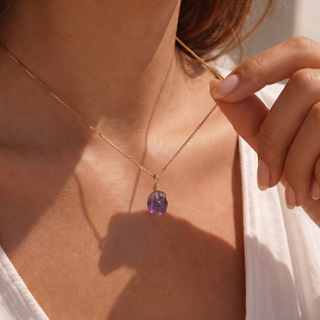 Amethyst Rohstein am Hals mit den Fingern angehoben, Seitenlicht