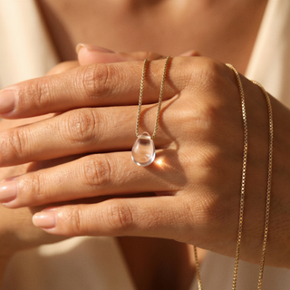 Rock crystal teardrop on spread fingers, gold chain around the hand