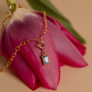 Aquamarin Anhänger am goldenen Armband auf einer Tulpe