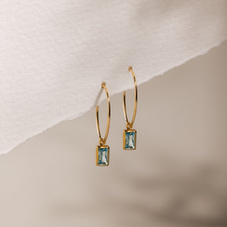Aquamarin Creolen Ohrringe in Gold: feine Creolen mit facettiertem Aquamarin an einem Papierrand