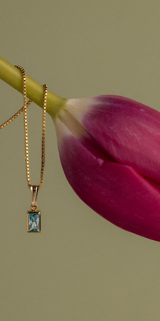 Aquamarine necklace on a tulip stem against a green background