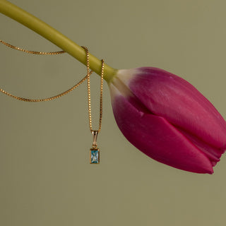 Aquamarin Kette an einem Tulpenstiel vor grünem Hintergrund