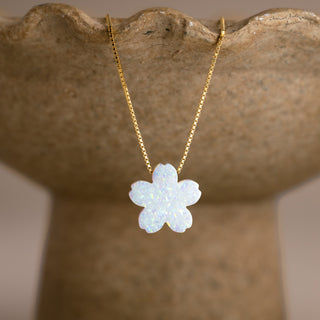 Synthetic Opal Flower Necklace in gold with a white cherry blossom on a stone-colored bowl