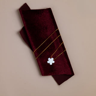 Flower necklace in gold on a dark red velvet cloth