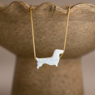 Dackel Kette in Opal-Optik in Gold mit weißem Dackel an einer steinfarbenen Schale
