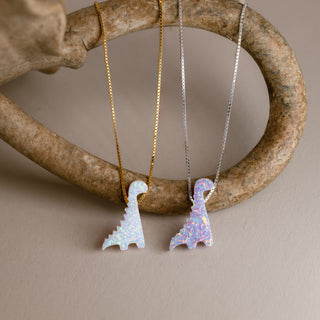 Dinosaur necklace in gold with a white dinosaur and in silver with a lilac dinosaur on a curved ring
