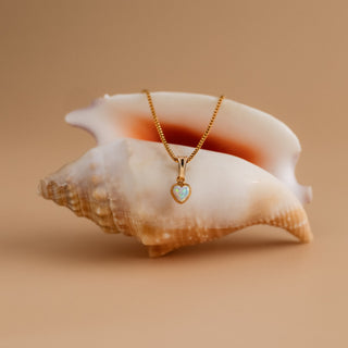 Kette mit Opal über einer großen Meeresschnecke drapiert