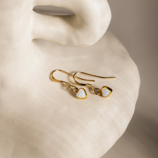 Opal earrings in gold on a light ceramic sculpture