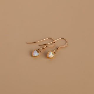 Pair of opal earrings with gold ear hooks on a warm background