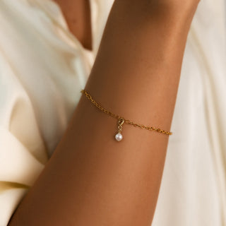 Armband mit Perle am Handgelenk getragen, feine Goldkette mit ovaler Perle