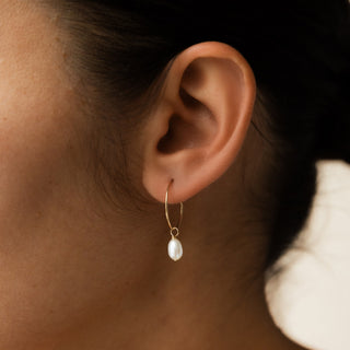 Creolen mit Perle getragen, feiner goldener Ring mit ovaler Perle am Ohr