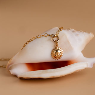 Detail: the sun hangs from the gold bracelet on a spring ring clasp