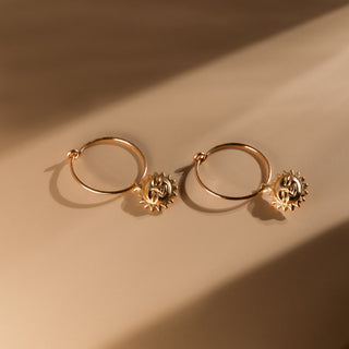 Paar goldene Creolen mit Sonne im warmen Licht