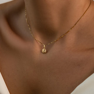 Kette mit Sonne getragen: goldener Sonnenanhänger am Dekolleté