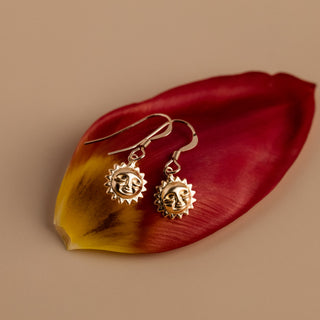 Sun earrings on a red petal