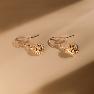 Pair of sun earrings with clear earring backs in warm light