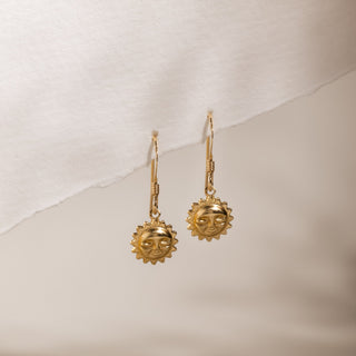 Sun drop earrings hanging from the edge of a sheet of paper